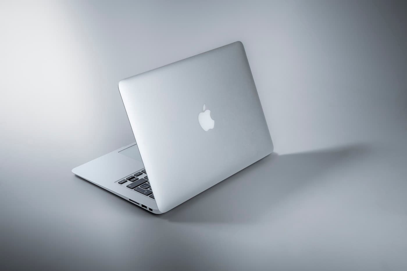 Silver MacBook Pro closed on a grey surface, Apple logo facing up